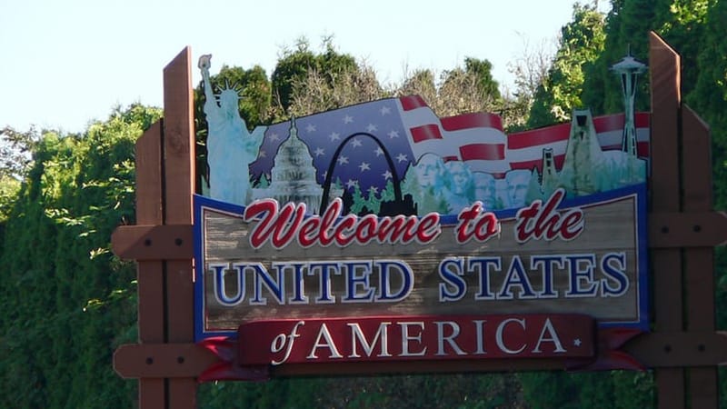Colorful wooden sign WELCOME TO THE UNITED STATES OF AMERICA featuring Statue of Liberty, US Capitol dome, Mount Rushmore, Golden Gate Bridge, and Space Needle.