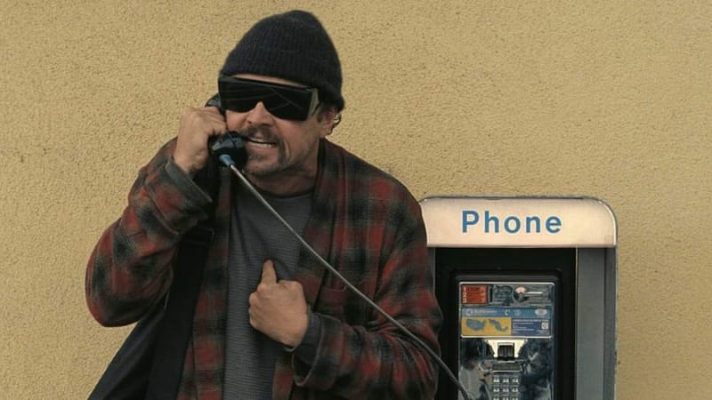 An angry Leonardo DiCaprio in big dark glasses and a Pendleton, nostrils flared, snarling into the handset of a 1980s pay phone