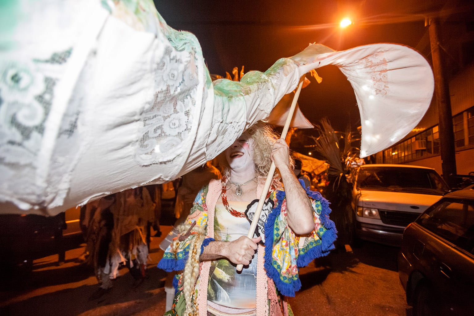 Partier smiling and holding the tail of a big fabric parade decoration