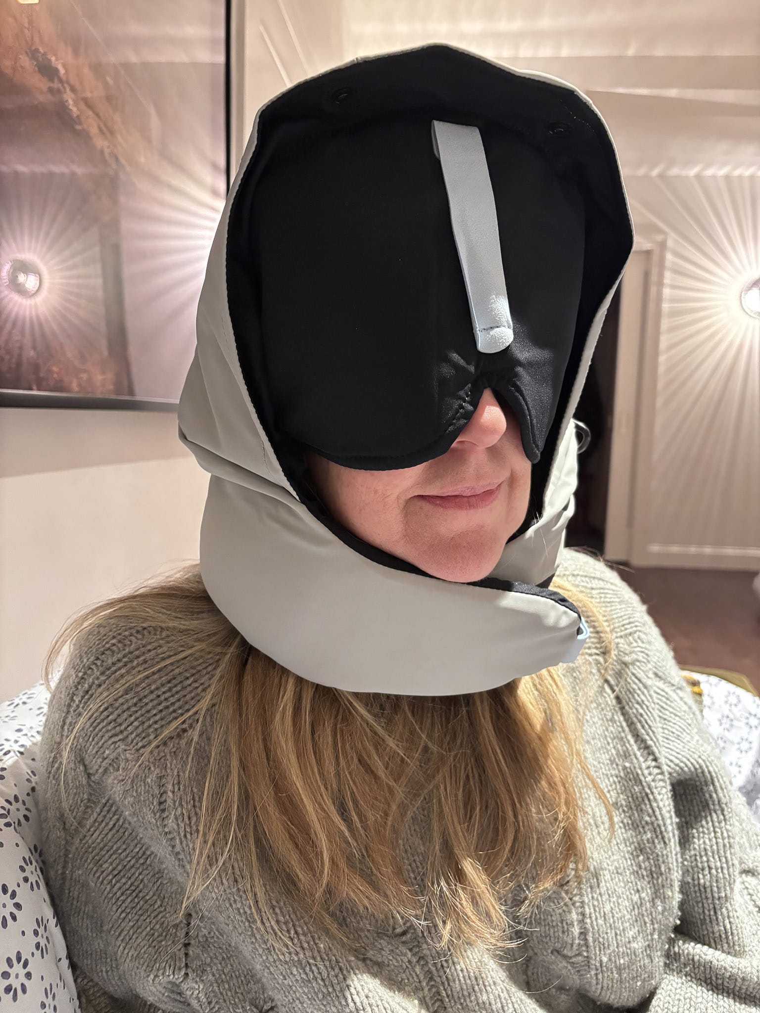 The author in a grey sweater and tall, elaborate sleeping hood with built-in black eye covering