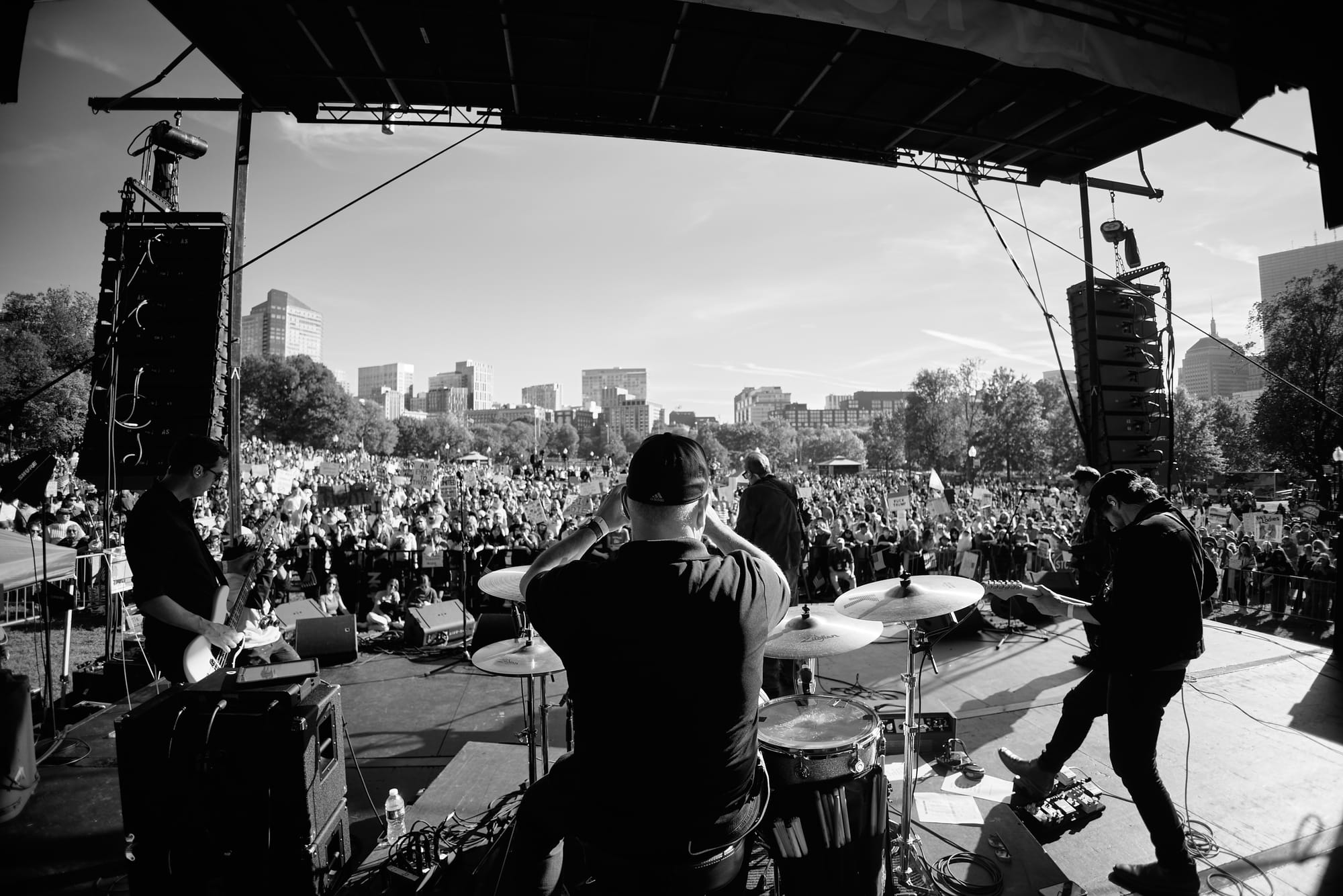 Black and white photo of an outdoor show, looking out from the stage at a big crowd