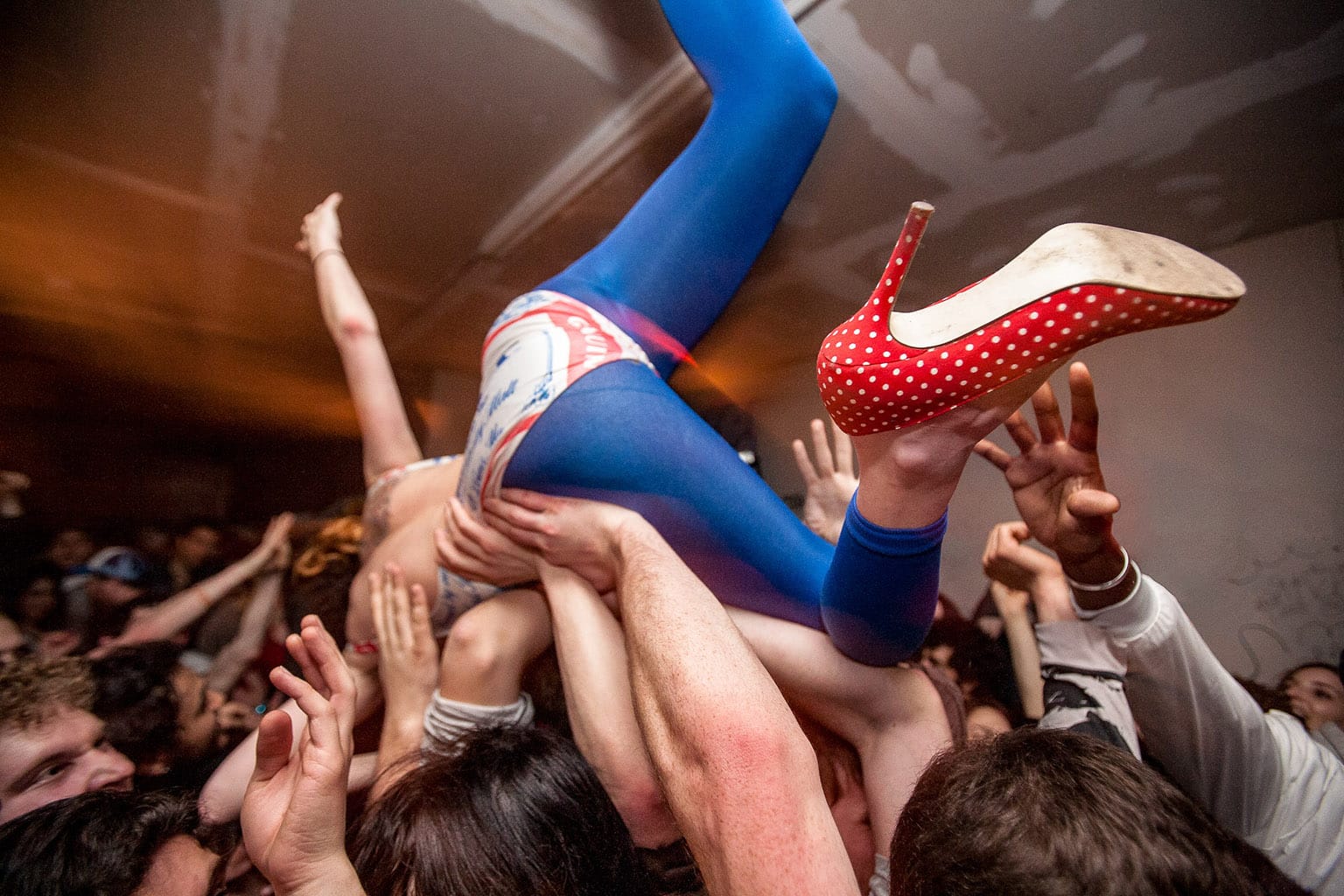 A person wearing tights and high heels crowd surfing