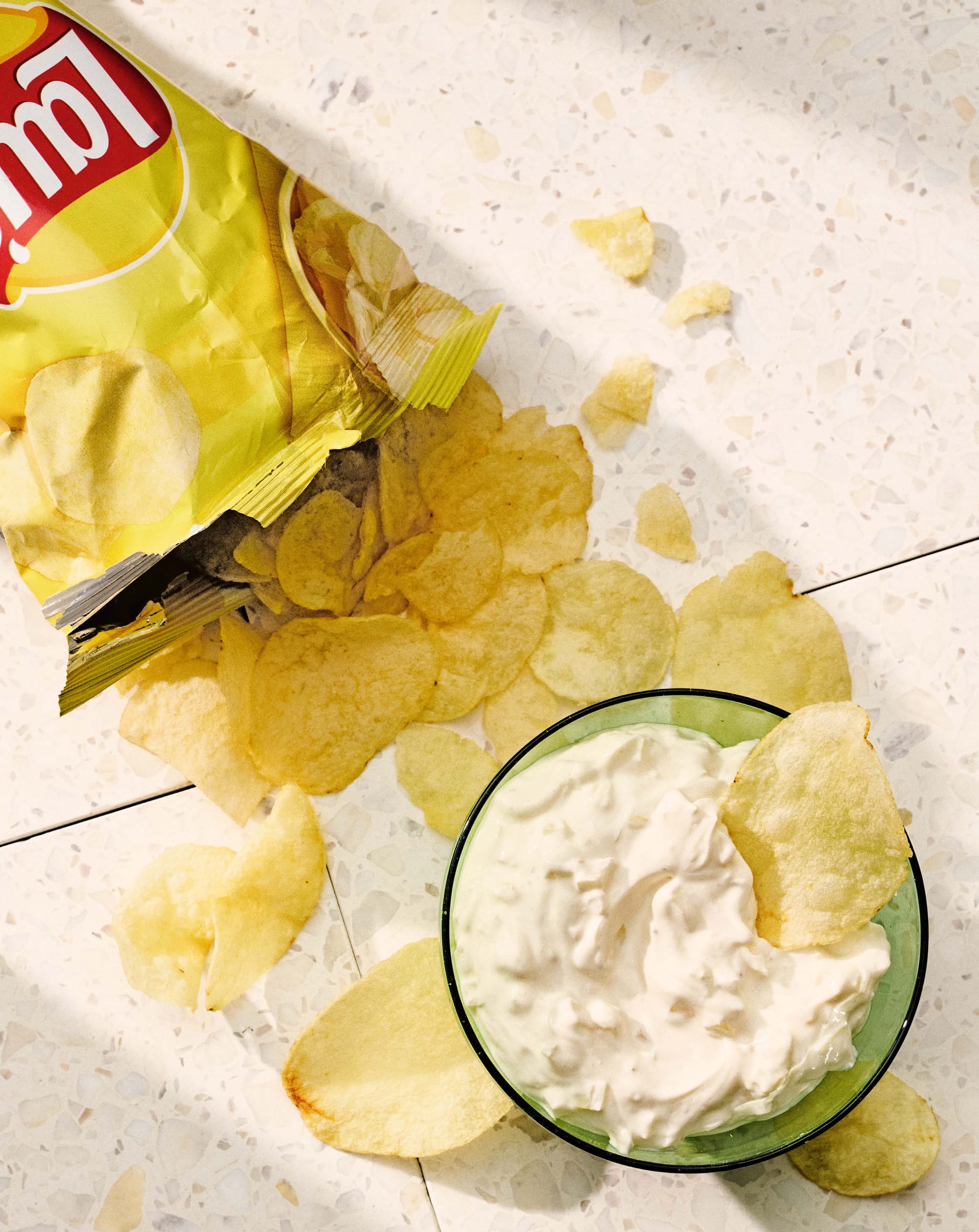 Chips and onion dip in a clear green glass bowl (yum)