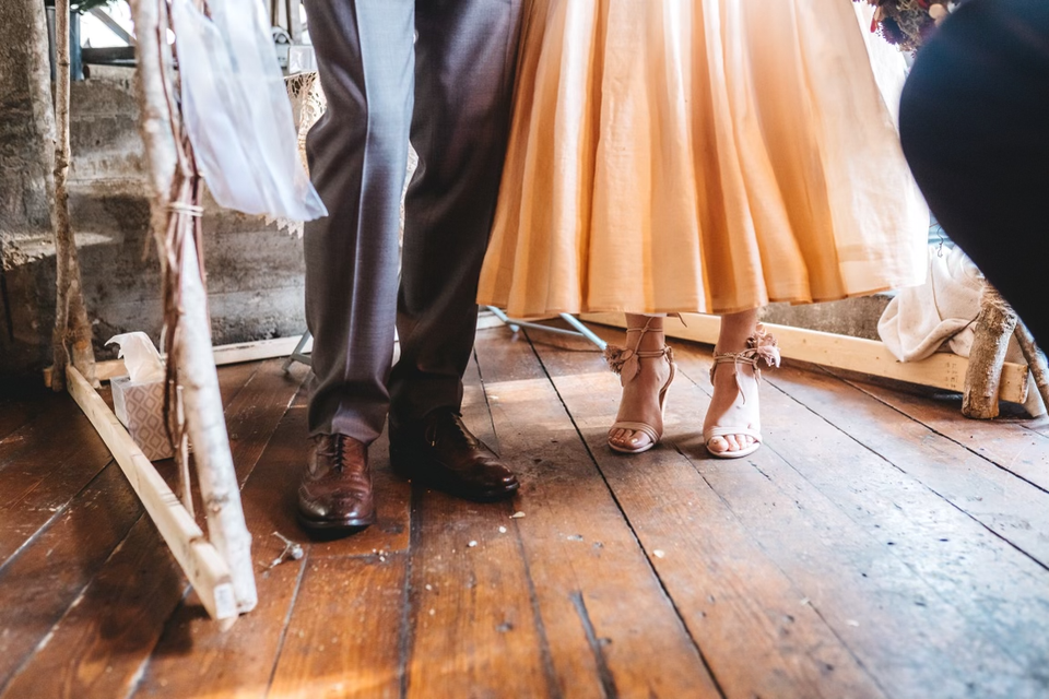 The beautifully shod feet of a handsome couple on a rustic wooden floor