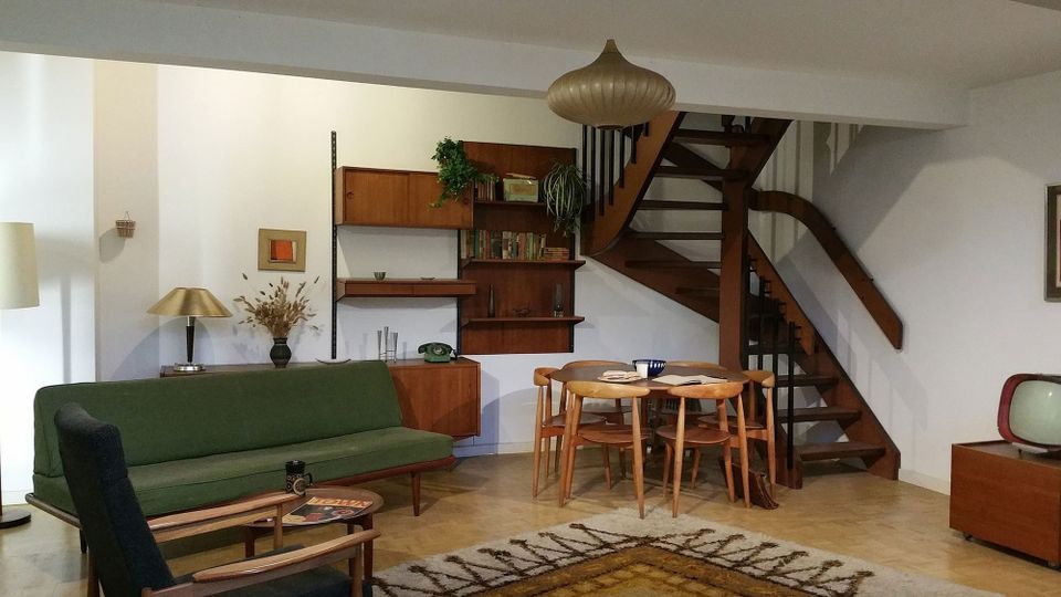 A mid-century modern apartment interior, compact and elegant, with Scandinavian rug and green minimalist sofa