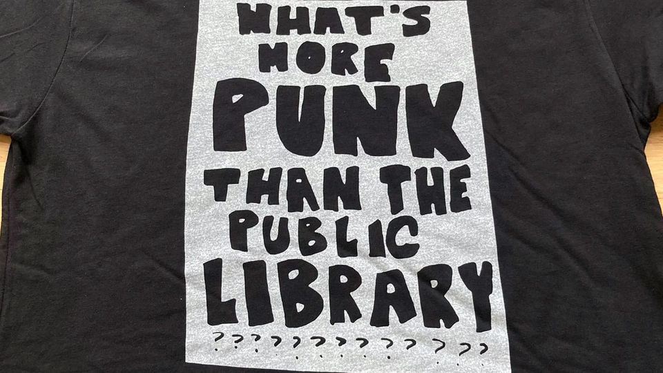 Black t-shirt with the printed message: WHAT'S MORE PUNK THAN THE PUBLIC LIBRARY???????