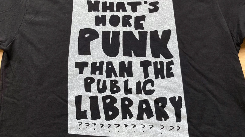 Black t-shirt with the printed message: WHAT'S MORE PUNK THAN THE PUBLIC LIBRARY???????