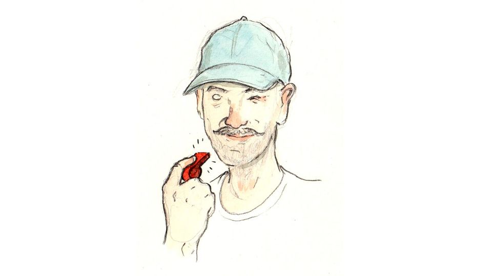 A mustachioed coach in a pale blue baseball cap and sly expression, holding a bright red whistle, and winking