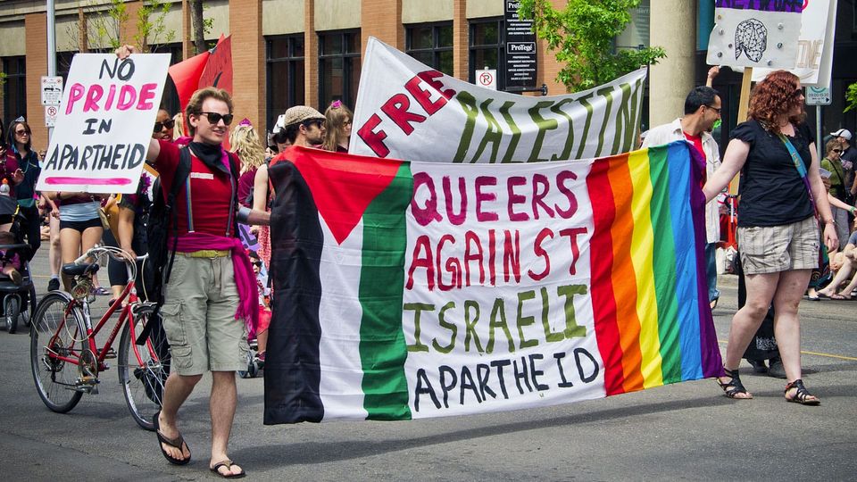 Edmonton Pride Parade 2011 photo shows colorful marchers with 'Queers Against Israeli Apartheid' banner
