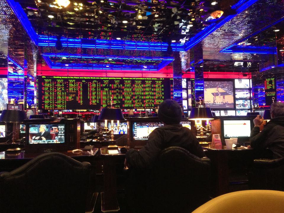 In a darkened casino in Reno, sports book appears on a huge screen, and basketball game on a small one