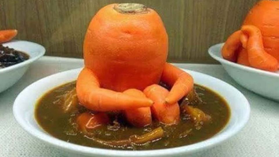 Meme image of a carrot sculpture resembling a person, seated in a bowl of soup
