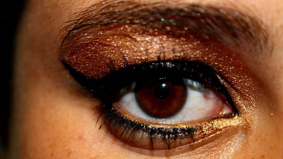 Close up on an eye with artfully applied eyeshadow and thick black winged eyeliner
