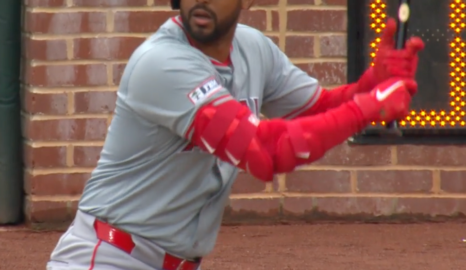 close up on a baseball player ready to swing. he's wearing red sleeves with red elbow guards on top