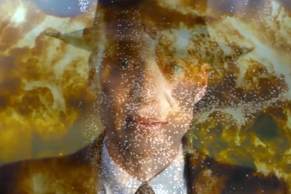 Portrait shot of Cillian Murphy as J. Robt. Oppenheimer in fedora and suit, melded with the image of a nuclear explosion