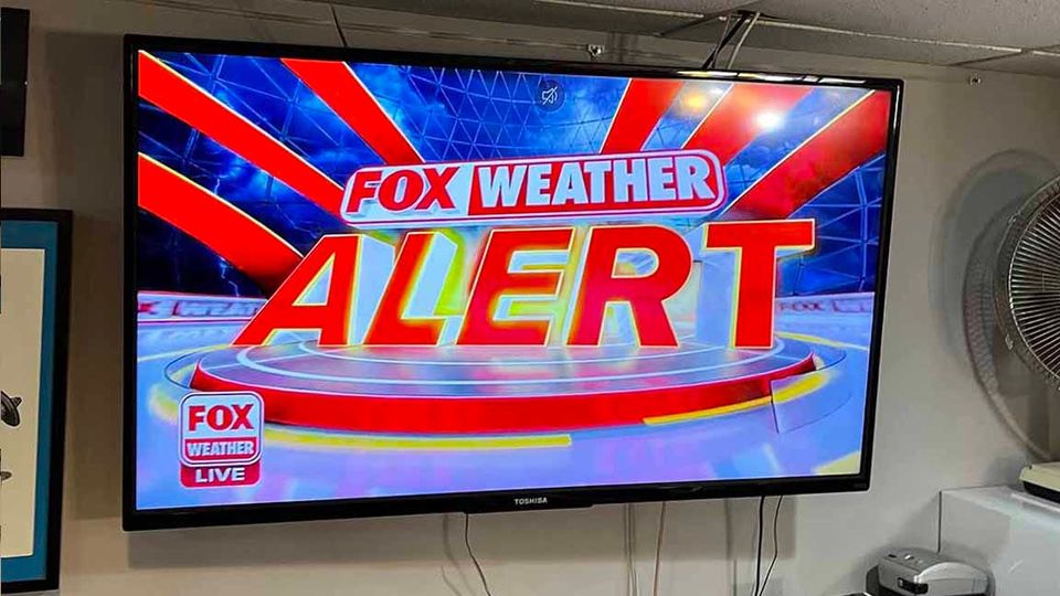 TV SCREEN: FOX WEATHER ALERT FOX WEATHER LIVE, glowing red and yellow with red rays emanating pure panic