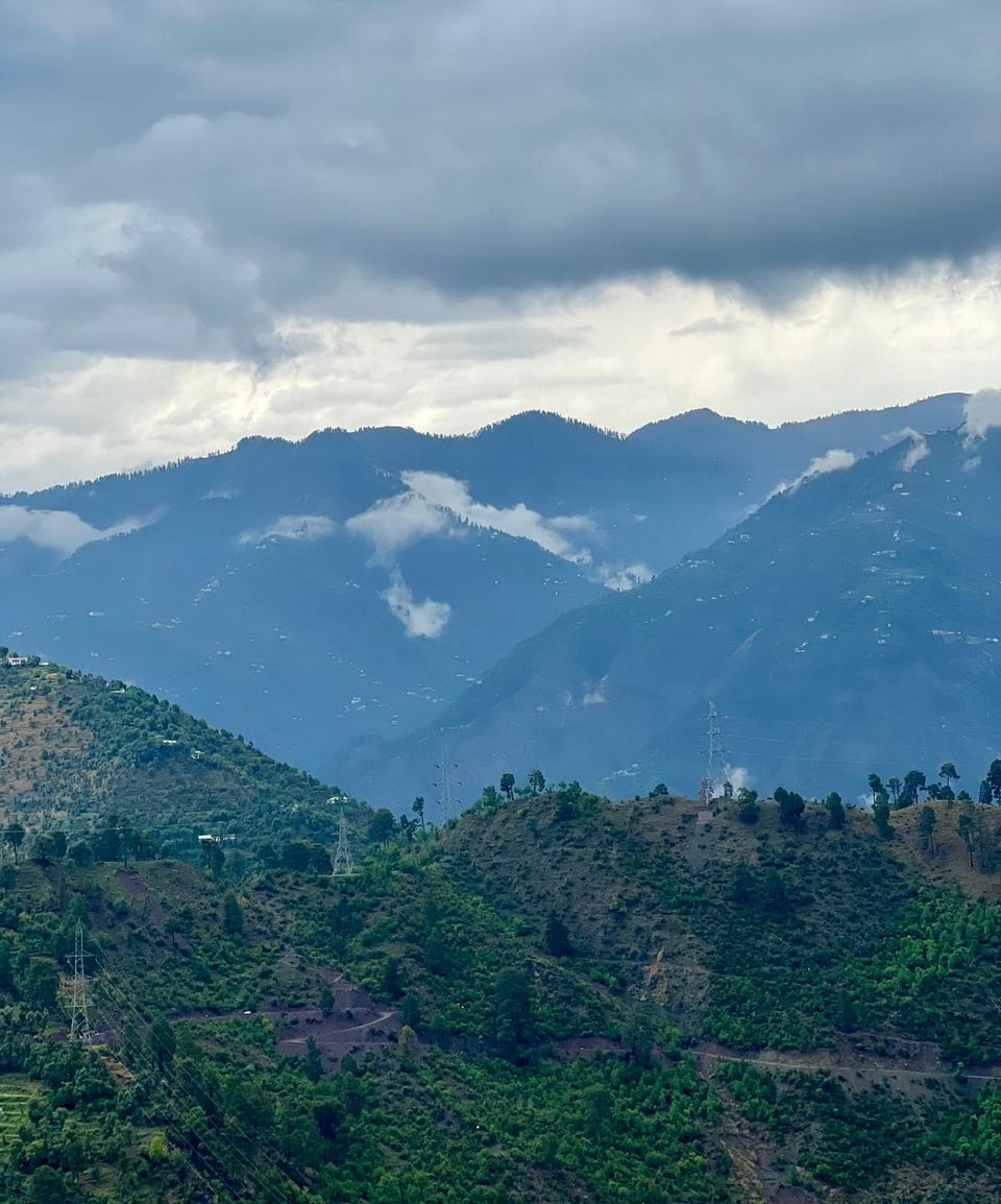 An extraordinary landscape in Kashmir, of vivid tree-covered hills, misty mountains and thick-clouded skies
