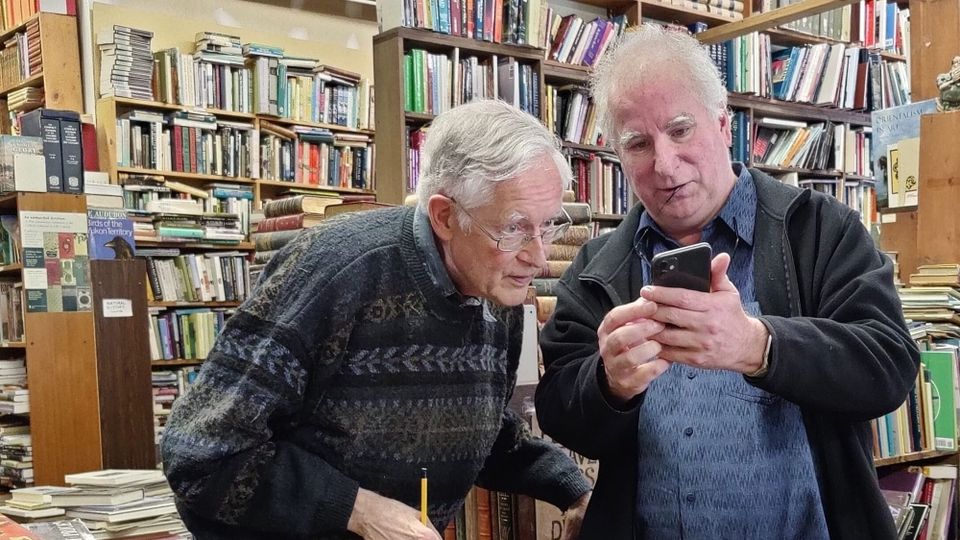 Brewster Kahle (with phone), talking with Don Stewart, at Don's legendary bookshop, MacLeod's Books, Vancouver, BC