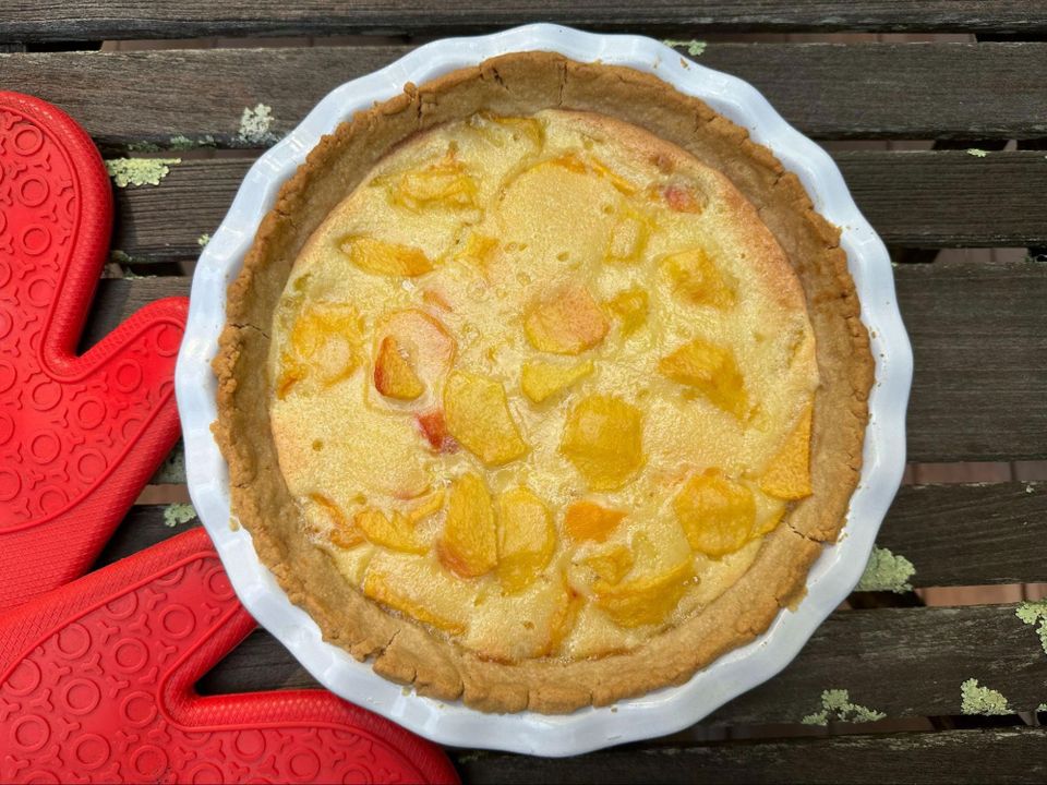 Just a luscious-lookin' pie on a picnic table with red baking mitts alongside WOWwwww