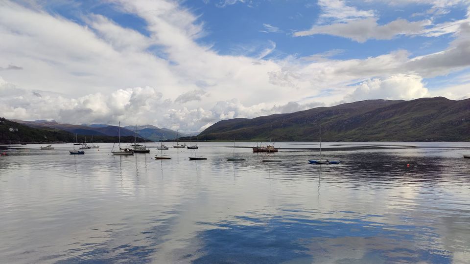 A view of Ullapool Harbor, with thrilling white clouds and dreamy blue sky reflected in the water