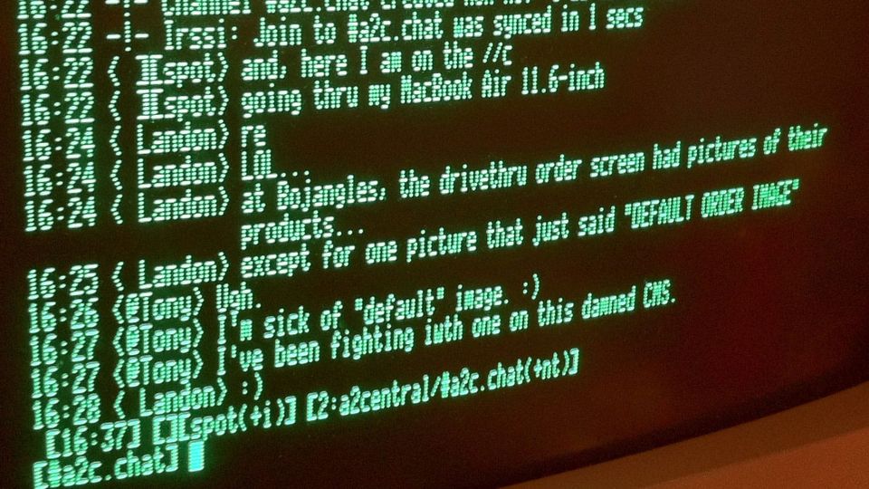 An old green-on-black monochrome monitor screen shows an IRC chat between <@Tony>, <Landon>, <][spot> et al.