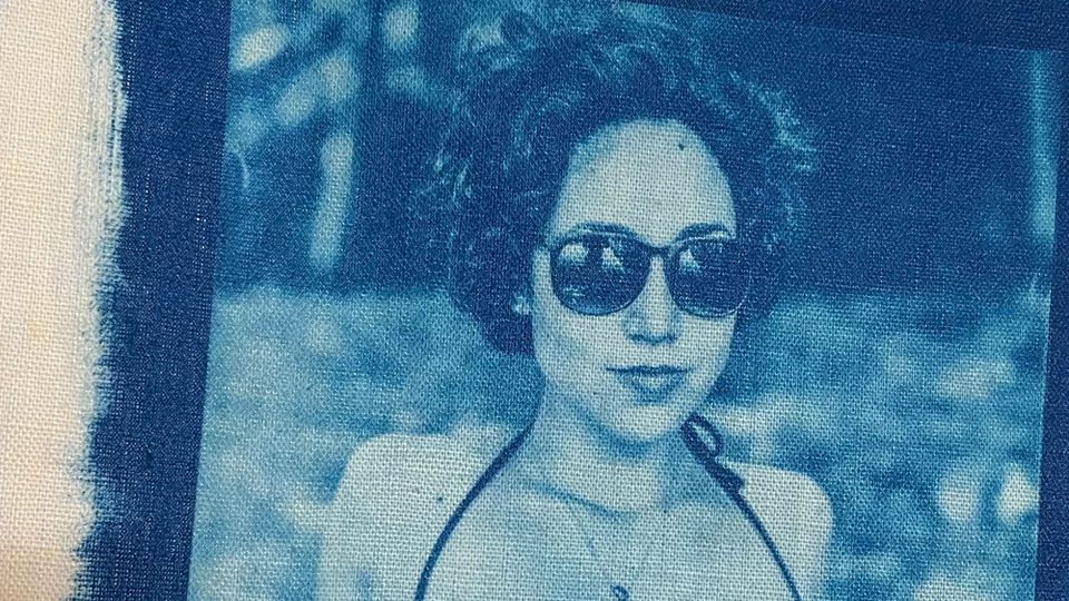 Cyanotype photo of the author, printed on canvas; she wears sunglasses, a bikini top and a pendant on a slender chain