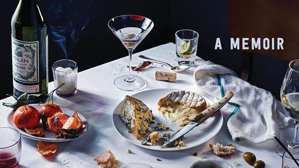 A table covered with a snow-white cloth bears the remains of a feast, with near-empty glasses, cheese plate, and fruit