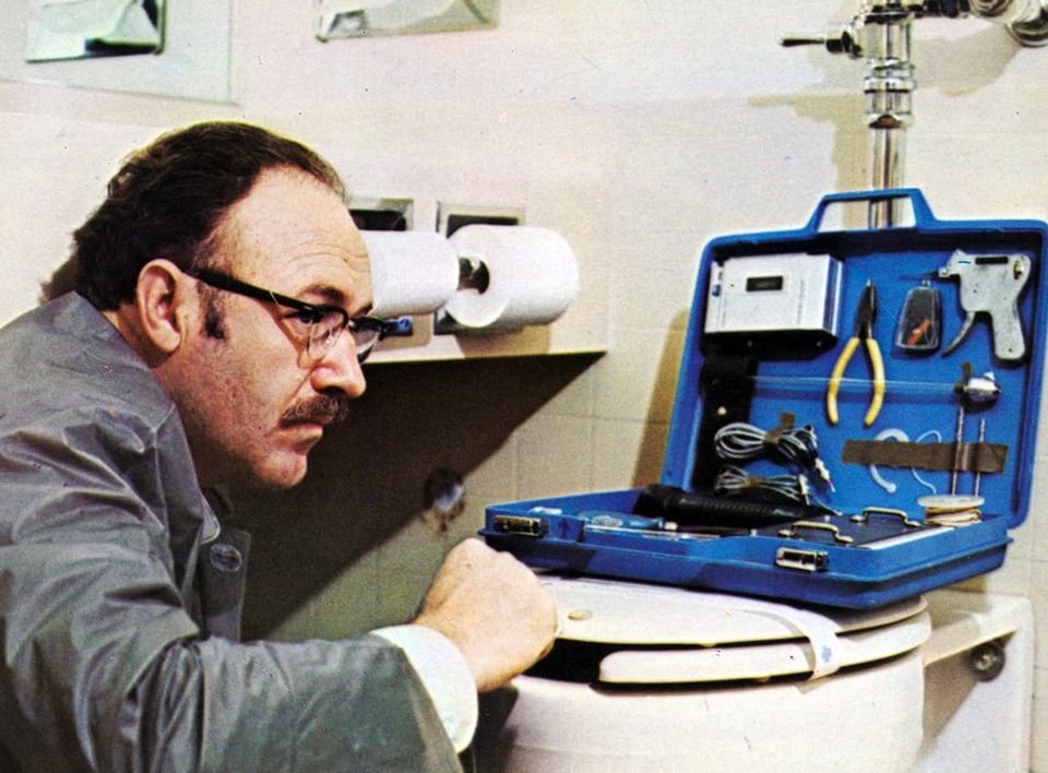 Hackman's character with nefarious listening devices set up on top of a toilet.
