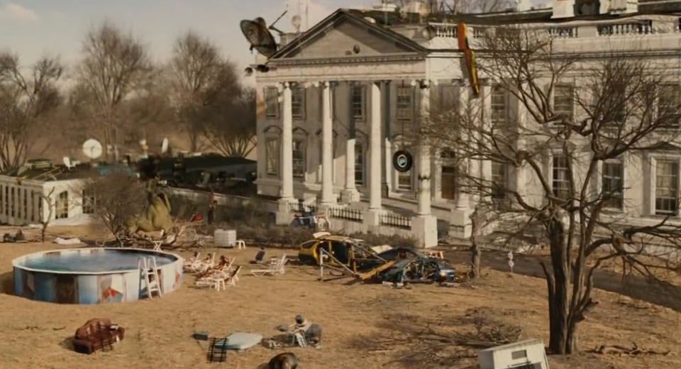 Movie back. The ruined White House, bare brown lawn, satellite dish, folding chairs, with above-ground pool, junked autos.