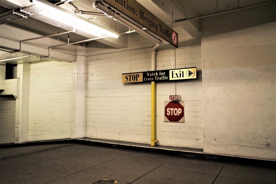 Interior of parking lot in downtown Los Angeles with scuffed cream painted walls fluorescent lighting and various STOP signs