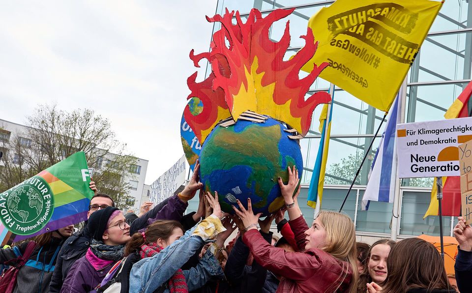 At recent demonstration in Berlin young people hold up a brightly painted papier-mache globe with cardboard flames