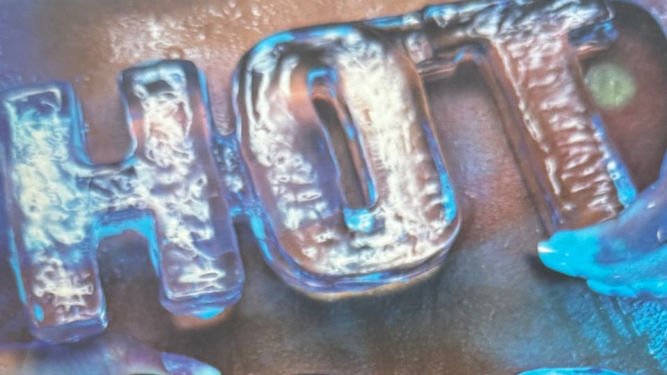 Detail of Maxim HOT 100 cover, supposed to be "HOT 100" carved out of ice, being held against a woman's abdomen.