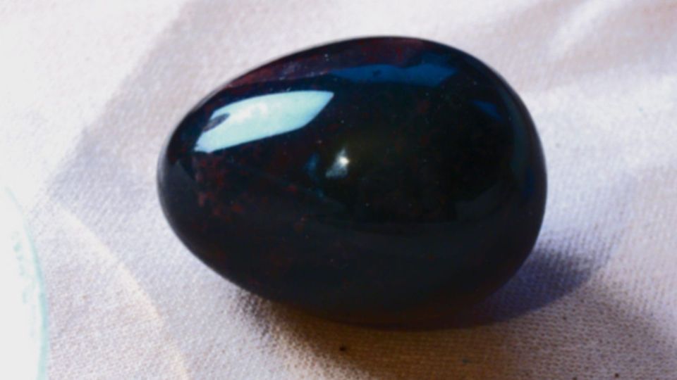 A glossy black egg on a pale fabric background