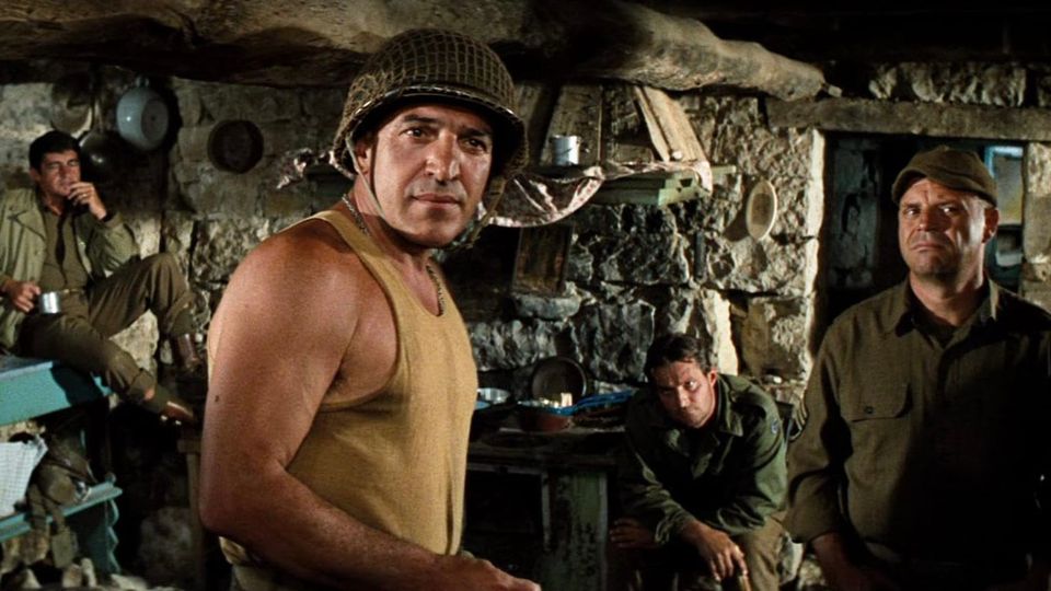 Telly in WWII Army helmet and undershirt, Rickles in Army cover and fatigues, and two other guys looking warily off camera 