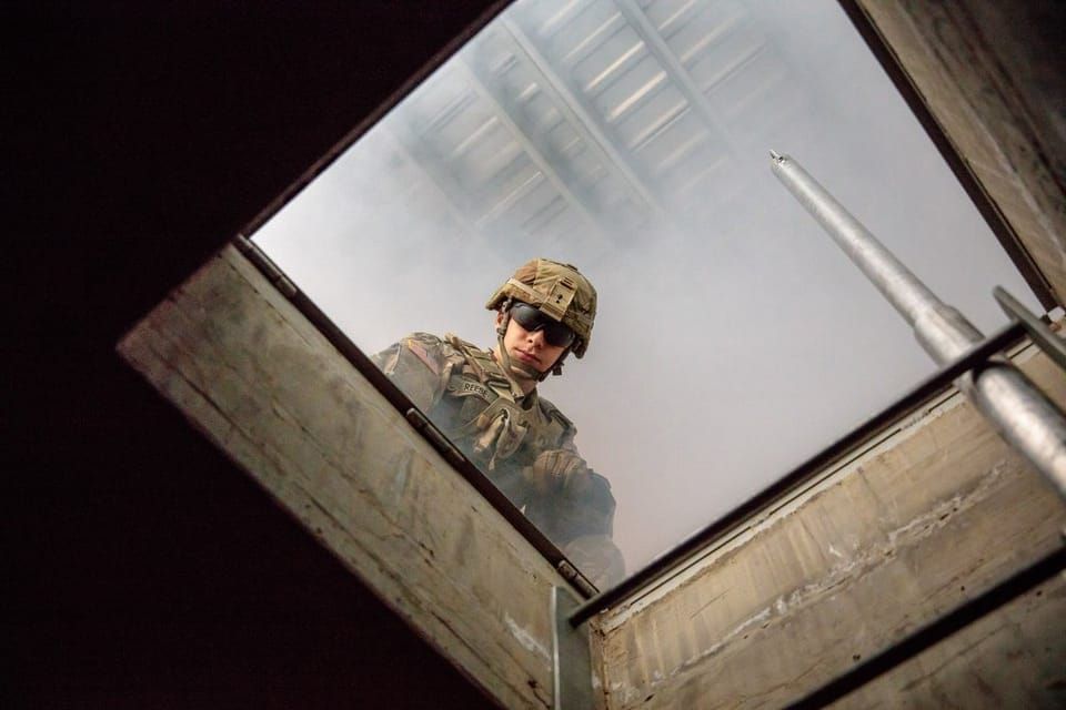 A soldier peering down into a tunnel