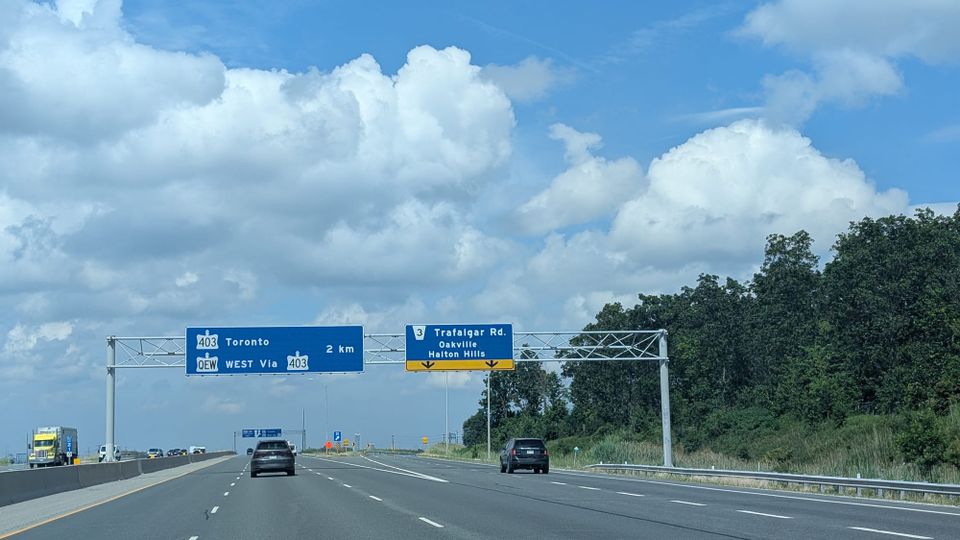 A hot-looking vivid blue summer sky with thick white clouds above the 403 highway to Toronto