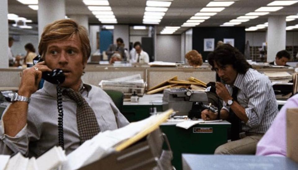 Robert Redford on the phone, Dustin Hoffman behind him, in the newsroom in 'All the President's Men' (1976)