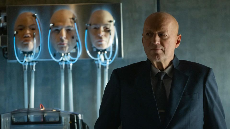 Atom in the villain's lair, with the masks of three faces not his own but they look like he can put them on maybe