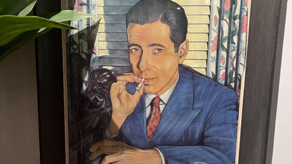 Painting in a wooden frame of Humphrey Bogart (in a scene from 'The Maltese Falcon' I believe) wearing a blue striped suit and red tie, smoking