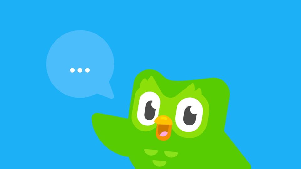 The Duolingo Owl with a speech bubble reading (...) on a bright blue background