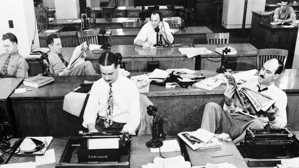 The New York Times newsroom in 1942, looks like a movie set with old black steel typewriters and a bunch of tough looking guys in shirtsleeves and ties hanging around at their desks