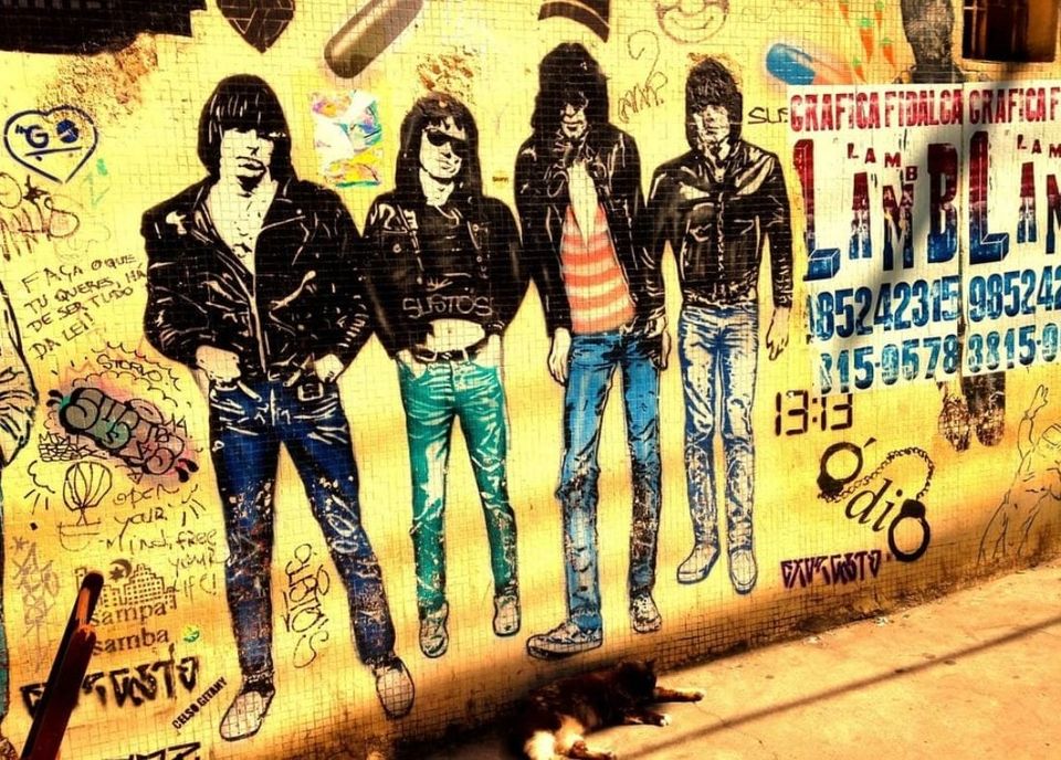 A golden wall with Portuguese graffiti ("Open your mind, free your life!") and a colorful stenciled image of the Ramones