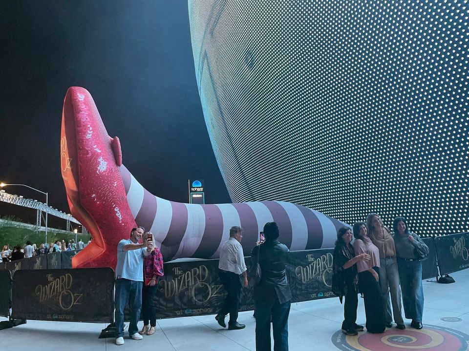 Tiny theatergoers before THE WIZARD OF OZ at the Las Vegas Sphere, beside the installation of 50-foot-long legs and 22-feet-tall ruby slippers