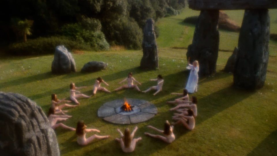 'Fire-jumping' fertility ritual from THE WICKER MAN (1973) of a stone circle with scantily-clad women seated around a log fire within