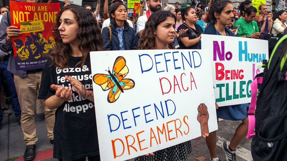 A September 2017 DACA rally in San Francisco. Young demonstrators hold signs reading "Defend DACA Defend Dreamers," "No Human Being Is Illegal," and "You Are Not Alone"