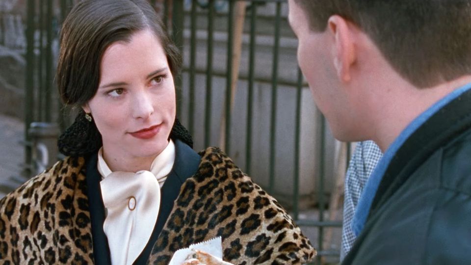 Parker Posey as Mary in PARTY GIRL (1995) wearing a leopard shrug over a dark wool jacket a and a thick cream satin tie neck blouse with a gold cravat pin at the throat
