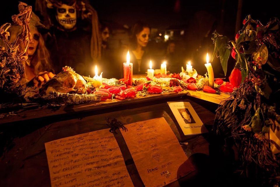 A small shrine for Nancy: night scene with people in masks, candles, prayers, flowers and a card "In loving memory of Nancy"