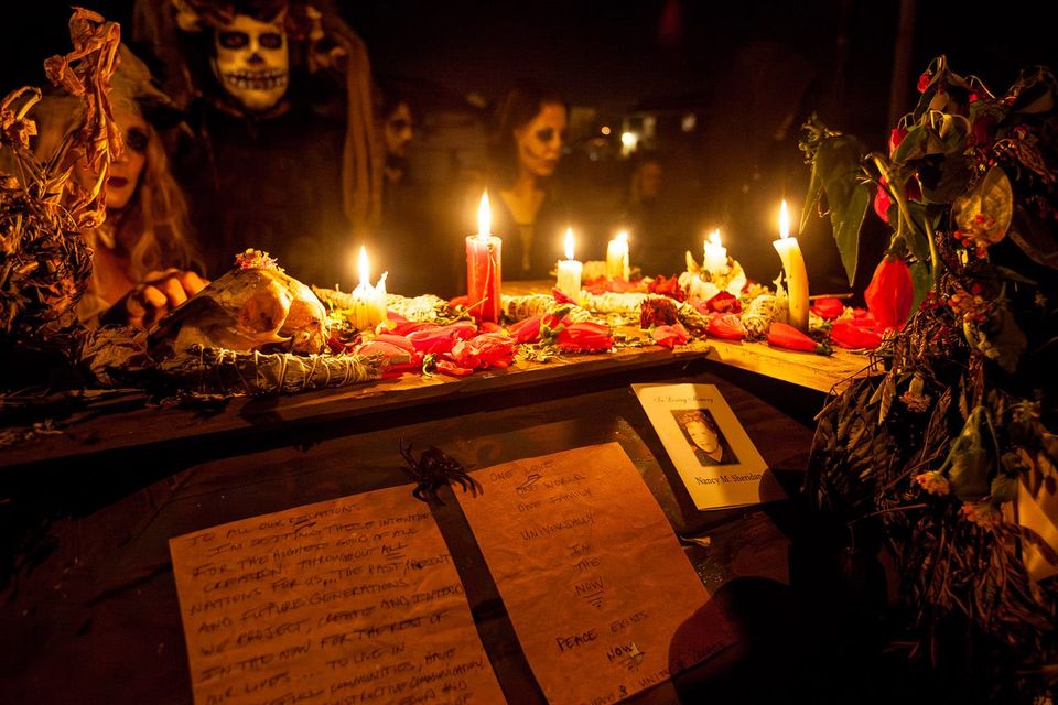 A small shrine for Nancy: night scene with people in masks, candles, prayers, flowers and a card "In loving memory of Nancy"