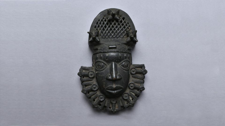Intricately stylized pendant mask of bronze and iron, lost wax casting from Benin made between late 16th and 19th centuries. 