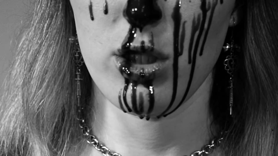 Lower part of a woman's face with ink (or chocolate!) dripping down her cheeks and nose in streams 