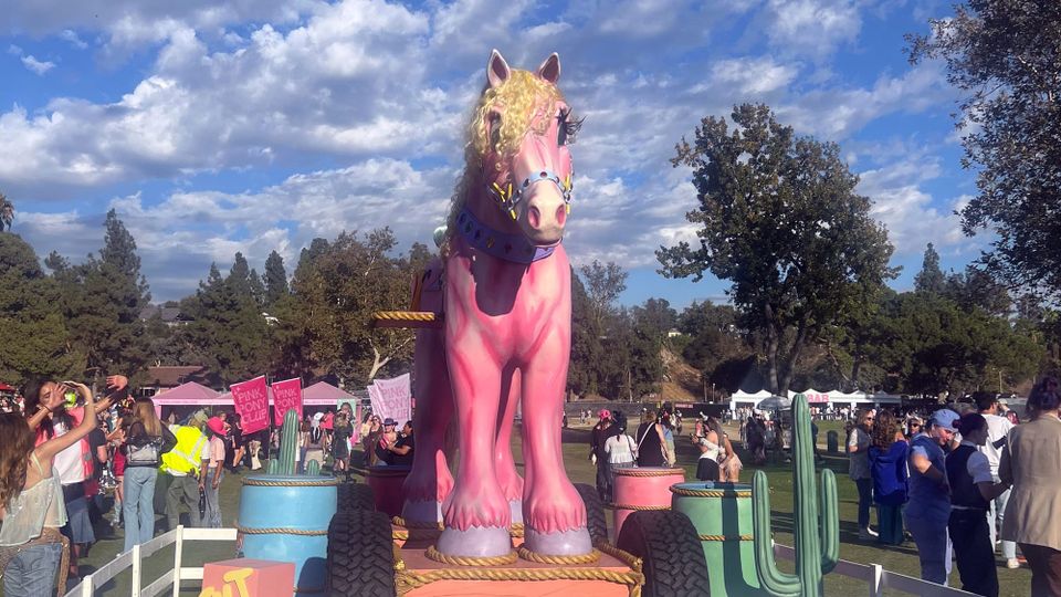 Gigantic pink pony sculpture on the grounds of the Pasadena Rose Bowl, with Chappell Roan fans milling about and taking photos